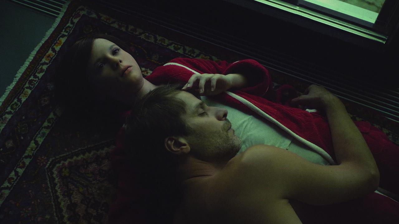 Dominik Warta umarmt schlafend Lena Watson am Boden liegend auf auf einem Perserteppich