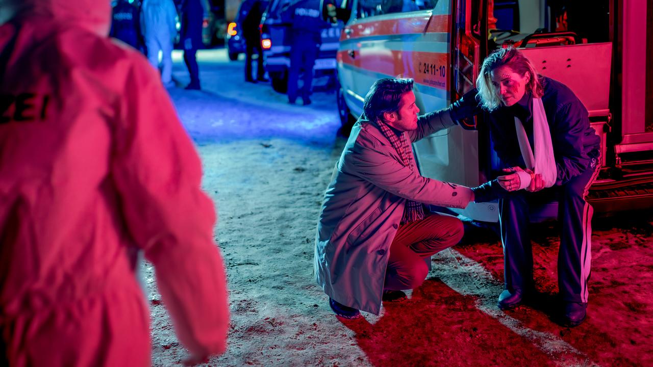Einsatzkräfte arbeiten nachts vor einem Rettungswagen, wo auch Lisa Kuen mit einer Armbandage von Alex Yüsüf-Demir betreut wird.
