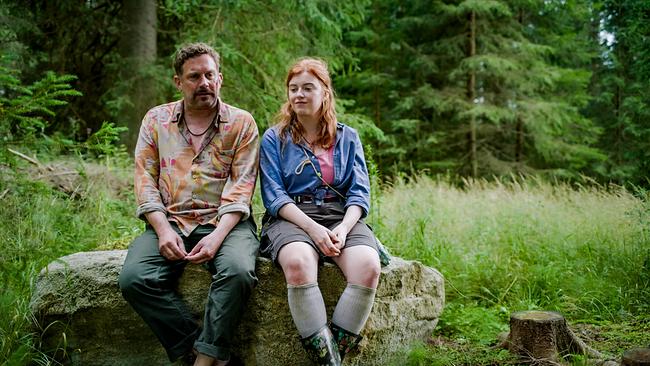 © ORF/AÖF Sebastian Bezzel und Máeve Metelka sitzen im Wald auf einem Felsbrocken