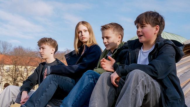 Die vier Jugendliche Silas John, Annika Benzin und Maximilian Reinwald sitzen entspannt im Freien auf einem Dach und blicken in die gleiche Richtung.