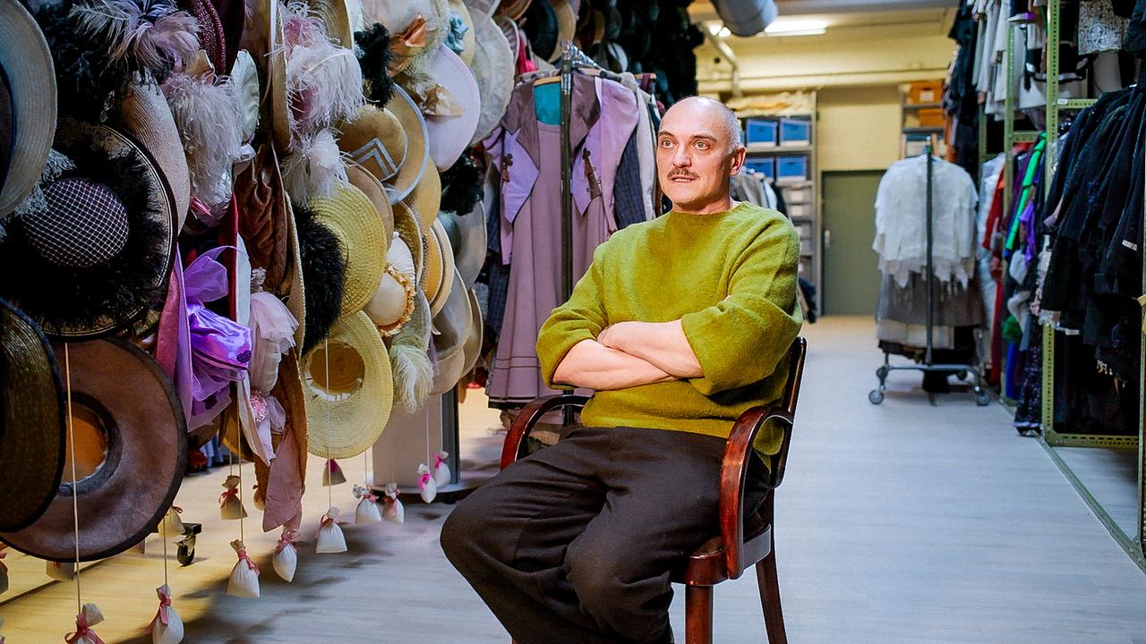 Regisseur Markus Schleinzer sitzt in einem Kostümfundus zwischen Kleiderständern und zahlreichen Hüten.