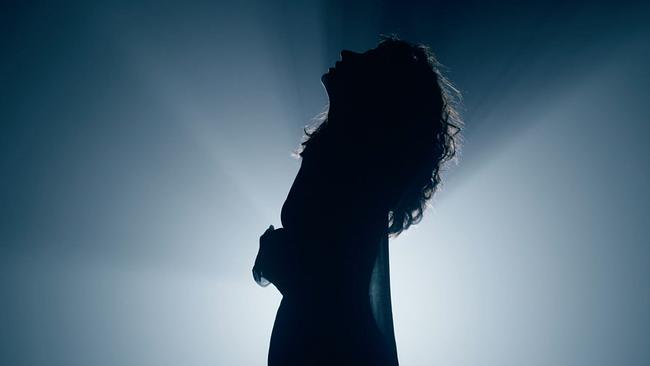  Silhouette einer Frau mit langen Haaren vor einem Lichtspot