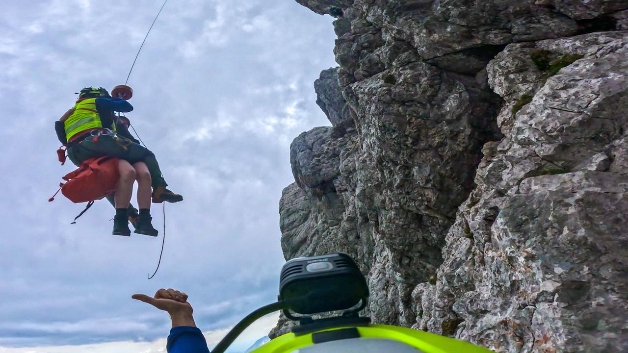 © ORF/BR/Timeline Production Abtransport eines Patienten bei einem Einsatz der Bergwacht Ramsau: Ein Bergretter seilt eine Person an einer steilen Felswand ab.