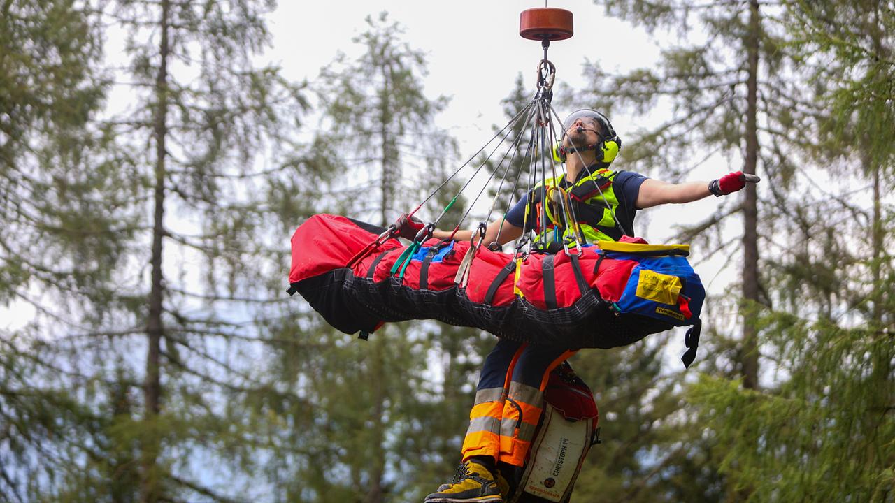 Einsatz der Bergwacht Ramsau: Ein Rettungssanitäter wird gemeinsam mit einer verletzten Person auf einer Trage per Seilwinde aus einem Waldgebiet geborgen.