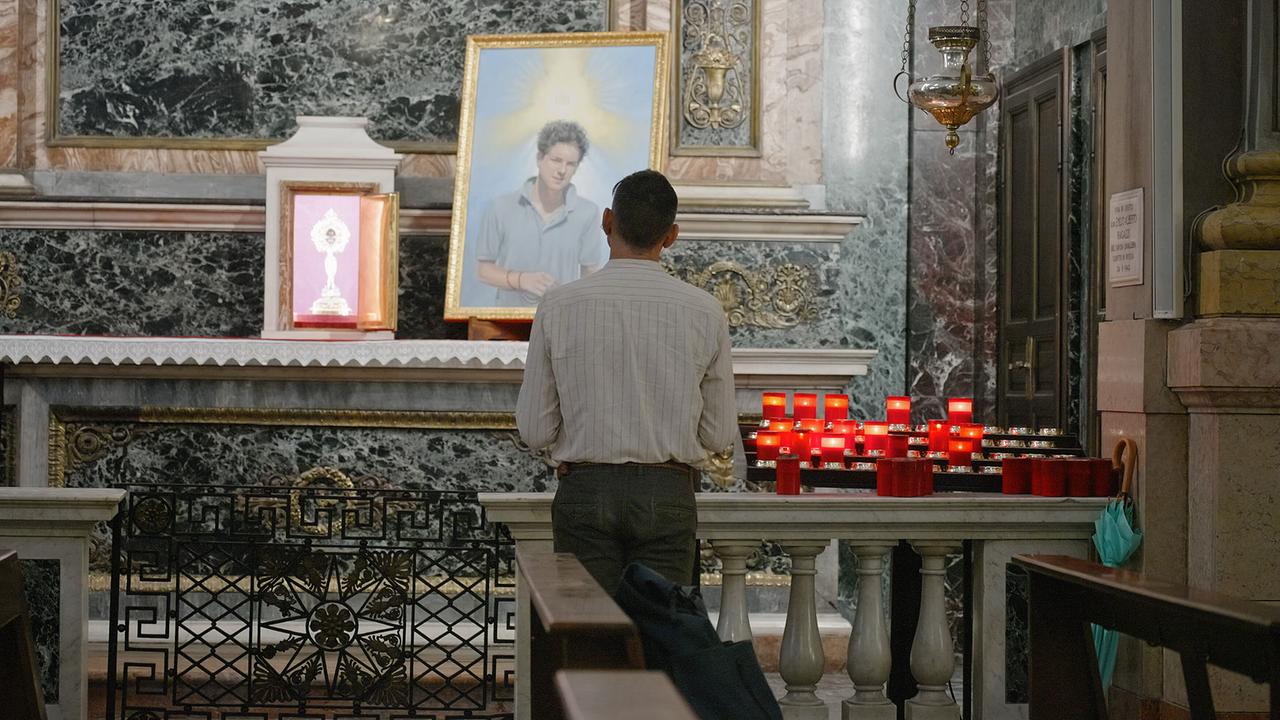 Ein Gläubiger steht in der Mailänder Kirche Santa Maria Segreta vor einer Reliquie von Carlo Acutis.