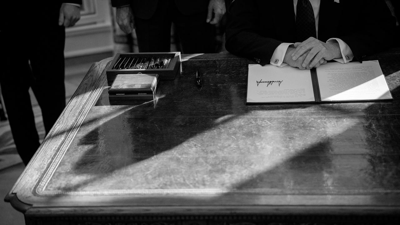 © ORF/Arte/Getty Images/Andrew Harnik Schwarz-weißes Foto eines Schreibtisches, auf dem ein von Trump unterzeichnetes Dekret liegt, auf dem die Hände des Präsidenten ruht