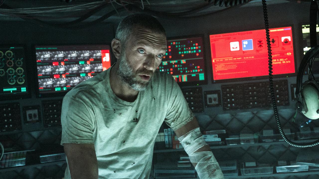 © ORF/Disney/20th Century Studios/TSG Entertainment/Alan Markfield Vincent Cassel als Kapitän Lucien steht in einem Kontrollraum mit Bildschirmen, mit verschmutztem T-Shirt bekleidet und einem Verband an seinem verletzten Arm schaut er sein Gegenüber ernst an