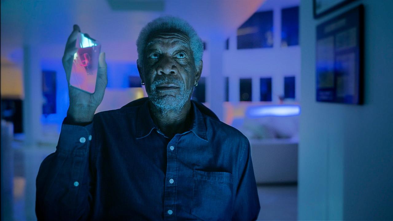 © ORF/Wild Bunch Germany GmbH/David R. Gaynes Morgan Freeman sitzt als Damon im Rollstuhl, er hält in seiner rechten Hand ein Handy hoch und blickt nach oben