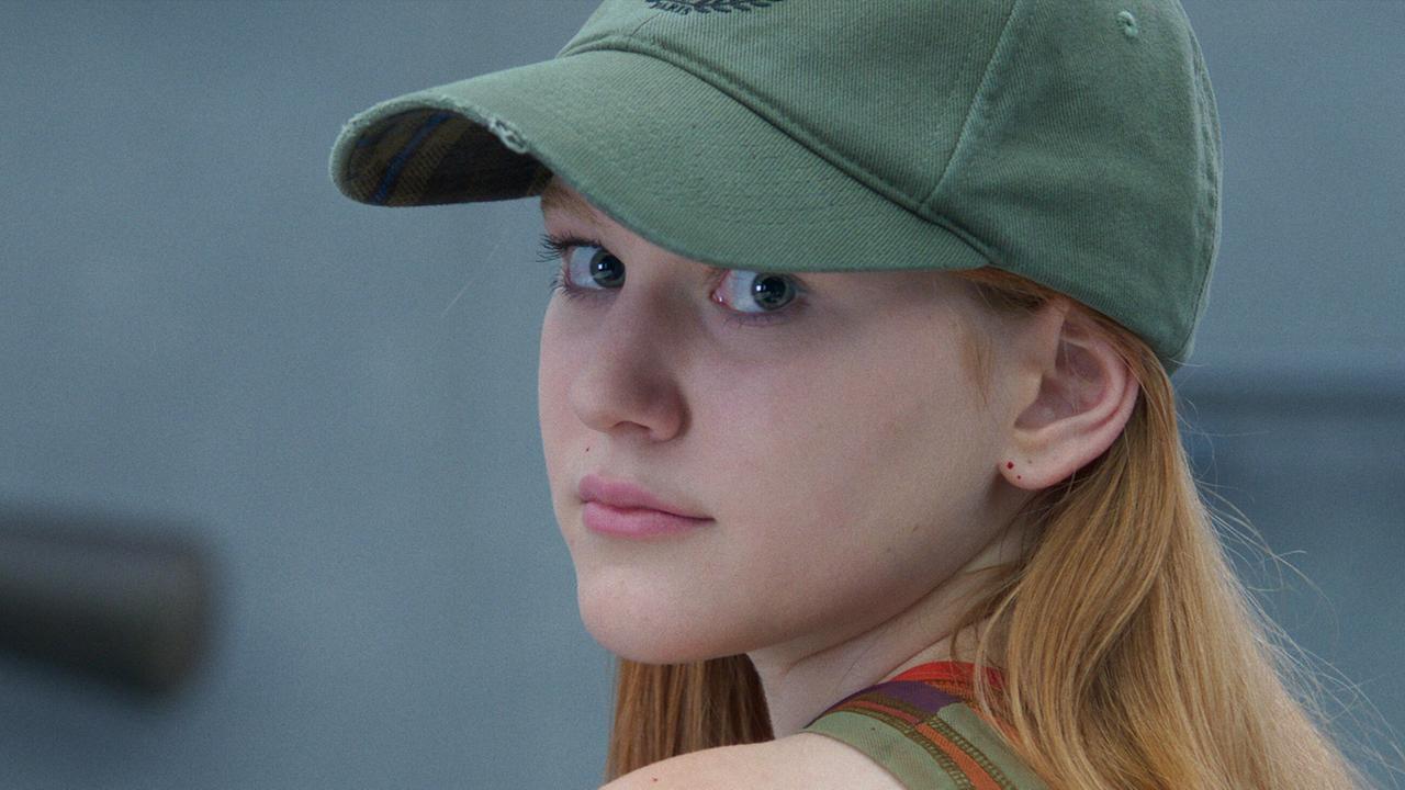 Paula Maynard, eine junge Frau mit Baseballkappe, blickt über ihre Schulter in die Kamera.