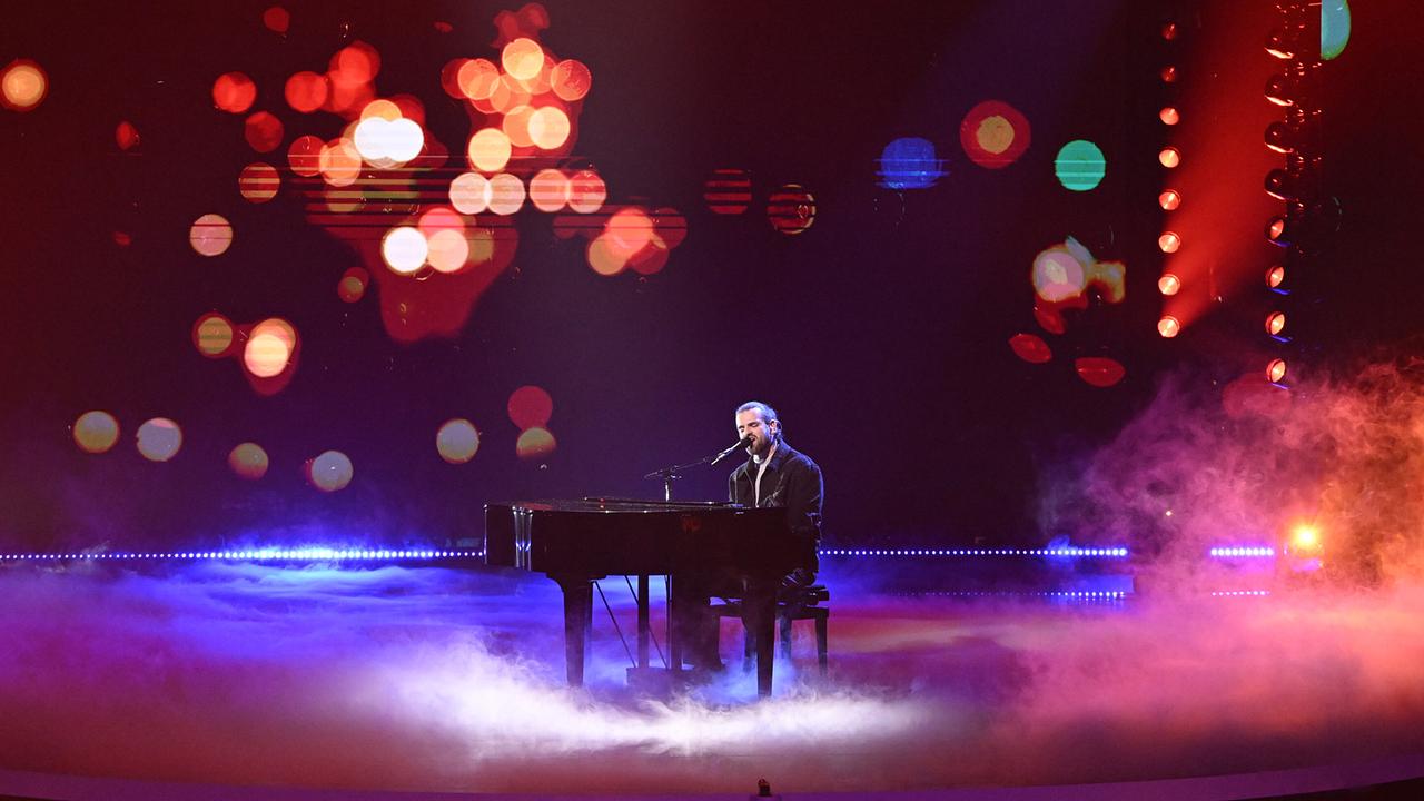 Sidrit Vokshi spielt am Flügel in einer nebeligen, dunkel gehaltenen Szene mit bunten, unscharfen Lichtpunkten im Hintergrund.