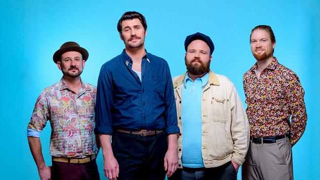 Die Gruppe Reverend Stomp, vier Männer,  vor blauem Hintergrund in farbigen, gemusterten Hemden und lässiger Alltagskleidung.