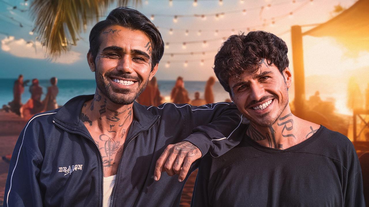 © ORF/Bavaria Media GmbH Zwei freundlich lächelnde junge tätowierte Männer vor einer Strandkulisse mit Palmen, Lichterketten und warmen Sonnenuntergangslicht