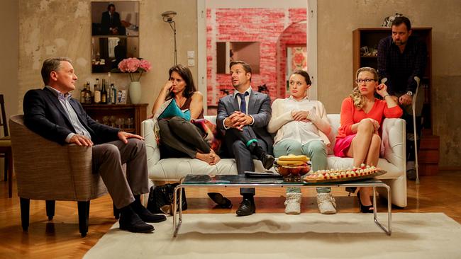 Hadrian Melzer, Waltraud Steinberg, Joachim Schnitzler, Maria Schneider und Nicoletta Huber sitzen in einem Wohnzimmer rund um einem Coachtisch beisammen, während Georg Schneider auf Krücken im Hintergrund dabei steht.