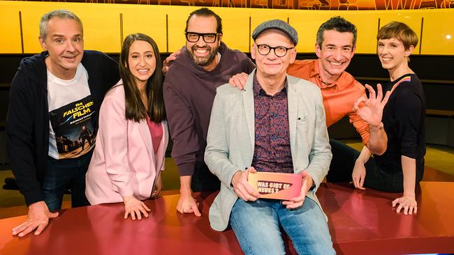 Thomas Maurer, Lydia Prenner-Kasper, Gerald Fleischhacker Omar Sarsam und Sonja Pikart stehen um Oliver Baier, der auf dem Moderatorentisch sitzt, im "Was gibt es Neues?"-Studio