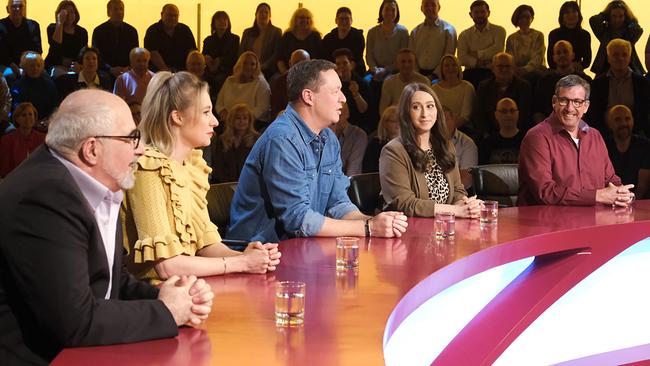 Michael Niavarani, Jennifer Frankl, Alex Kristan, Lydia Prenner-Kasper und Viktor Gernot sitzen nebeneinander am Ratepult von "Was gibt es Neues?" mit Publikum im Hintergrund.