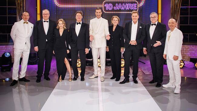 Gruppenfoto mit Wotan Wilke Möhring, Oliver Welke, Michelle, Tobias Moretti, Kai Pflaume, Mariele Millowitsch, Dieter Bohlen, Elton und Bernhard Hoëcker auf einer festlich beleuchteten Studiobühne vor dem großen Jubiläumslogo der Quizshow „Wer weiß denn sowas? – 10 Jahre“.