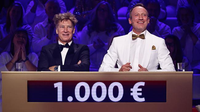 © ORF/NDR/Morris Mac Matzen Tobias Moretti und Wotan Wilke Möhring sitzen am Quizpult bei "Wer weiß denn sowas XXL", während auf der Anzeige vor ihnen der Gewinnstand von 1.000 Euro leuchtet.