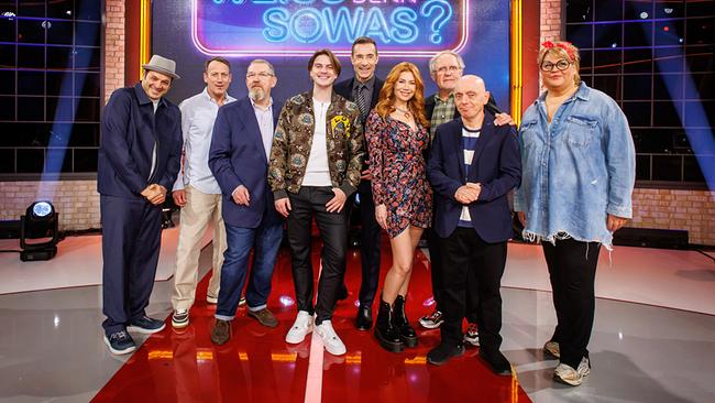 Gruppenfoto mit Kaya Yanar, Wotan Wilke Möhring, Dietmar Bär, Vincent Gross, Kai Pflaume, Palina Rojinski, Harald Krassnitzer, Bernhard Hoëcker und Ilka Bessin im Fernsehstudio vor dem leuchtenden Logo der Quizshow "Wer weiß denn sowas?".