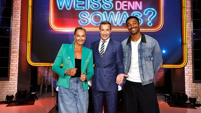 © ORF/NDR/ARD/Morris Mac Matzen Ex-Schwimmstar Franziska van Almsick, Kai Pflaume und der Weltmeister im Zehnkampf Leo Neugebauer posieren gemeinsam vor dem leuchtenden Schriftzug der Sendung „Wer weiß denn sowas?“.