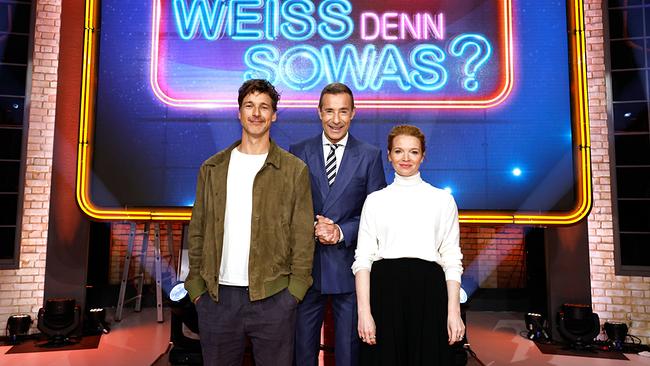 © ORF/NDR/ARD/Morris Mac Matzen Der Schauspieler Florian David Fitz, Kai Pflaume und die Schauspielerin Karoline Herfurth posieren gemeinsam vor dem leuchtenden Schriftzug der Sendung „Wer weiß denn sowas?“.