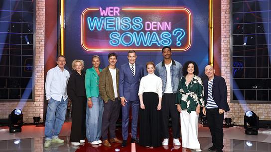 Wotan Wilke Möhring, Katja Riemann, Franziska van Almsick, Florian David Fitz, Kai Pflaume, Karoline Herfurth, Leo Neugebauer, Barbara Wussow und Bernhard Hoëcker posieren gemeinsam vor dem leuchtenden Schriftzug der Sendung „Wer weiß denn sowas?“.