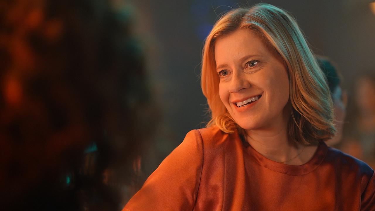 © ORF/Praherfilm/Nikolaus Geyrhalter Filmproduktion/Petro Domenigg Marie Theres in einem orangefarbenen Oberteil sitzt in einer gedämpft beleuchteten Umgebung.