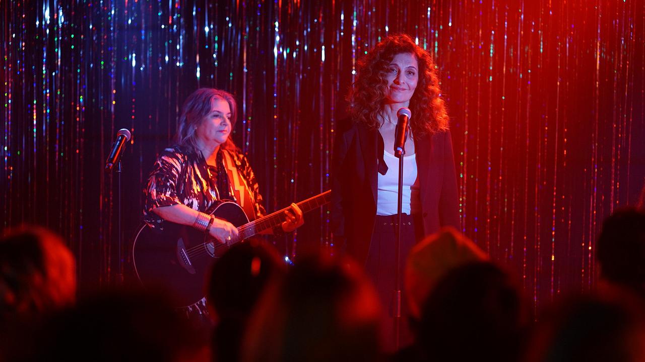 © ORF/Praherfilm/Nikolaus Geyrhalter Filmproduktion/Petro Domenigg Fa steht auf einer kleinen Bühne vor einem Mikrofon vor einem glitzernden Vorhang und rotem Bühnenlicht, neben ihr spielt eine Gitarristin.