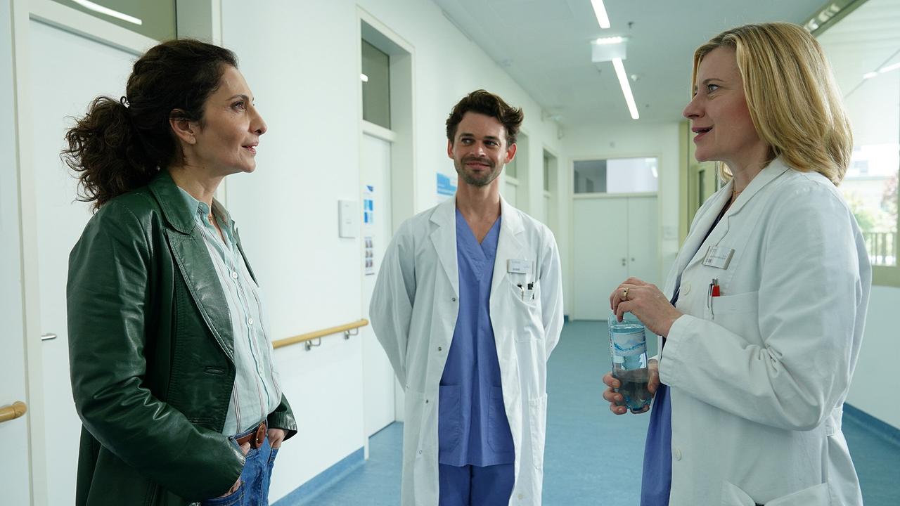 © ORF/Praherfilm/Nikolaus Geyrhalter Filmproduktion/Petro Domenigg Fa führt ein Gespräch mit Ärztin Marie Theres in einem hellen Krankenhausflur, im Hintergrund steht ein weiterer Arzt.