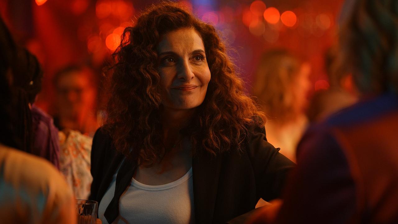 © ORF/Praherfilm/Nikolaus Geyrhalter Filmproduktion/Petro Domenigg In einer lebhaften Clubatmosphäre hält Fa ein Getränk, umgeben von weiteren Besuchern.