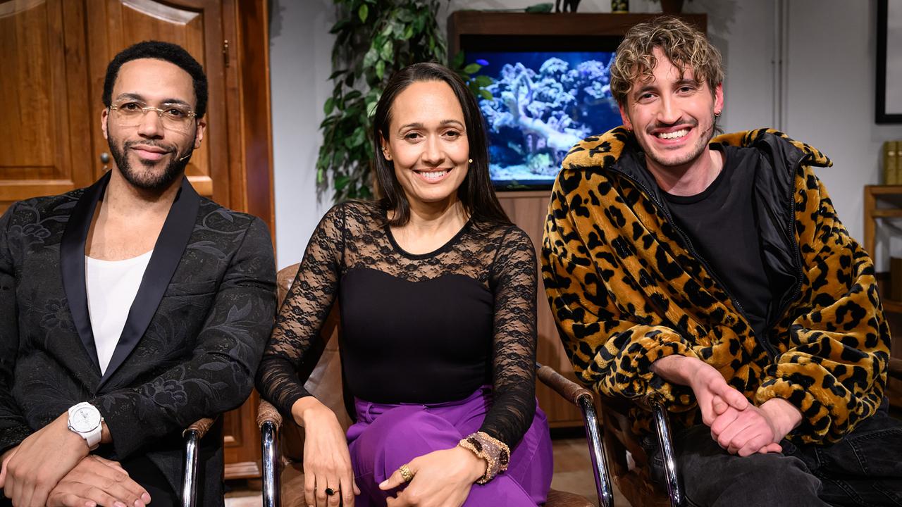 Cesar Sampson, Alice Tumler und Berni Wagner sitzen nebeneinander im "Willkommen Österreich"-Studio vor einem Aquarium und lächeln in die Kamera.