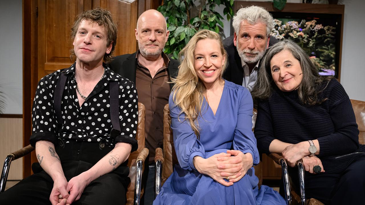 Voodoo Jürgens, Christoph Grissemann, Nina Proll, Dirk Stermann und Maria Hofstätter sitzen bzw. stehen beim Gruppenfoto im "Willkommen Österreich"-Studio vor einem Aquarium.