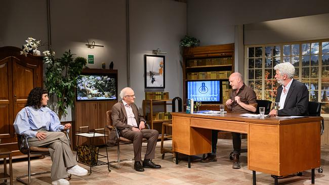 In einem gemütlich eingerichteten "Willkommen Österreich"-Studio sitzen Ina Regen und Reinhard Haller auf Sesseln und führen ein Gespräch mit Christoph Grissemann und Dirk Stermann, die an einem Holzschreibtisch sitzen.