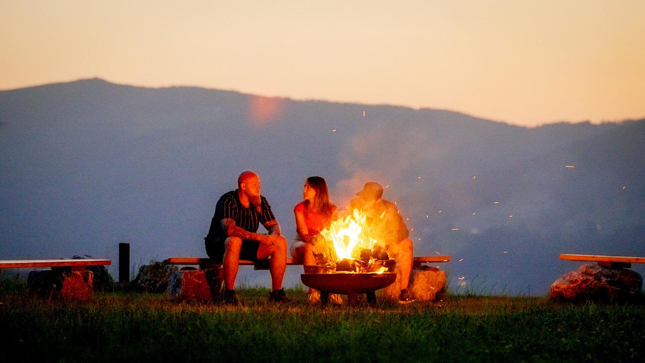 Kandidat Jürgen, Michelle Pippan und Kandidat Michael genießen den Sonnenuntergang am Lagerfeuer.