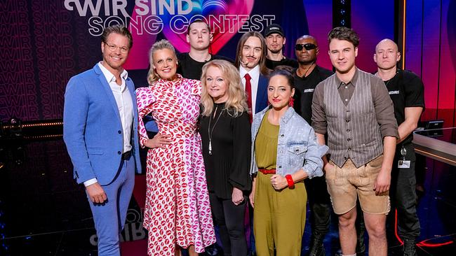 Gruppenfoto mit Mark Seibert, Barbara Schöneberger, Nicole, Caroline Athanasiadis, Tommy Cash und Chris Steger im TV-Studio vor dem Schriftzug „Wir sind Song Contest“.