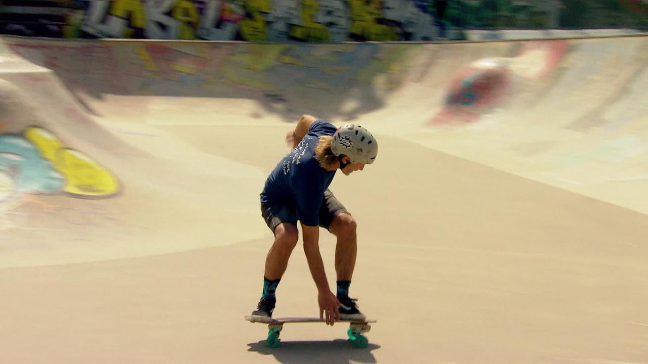 Skateboarder fährt mit Helm ausgerüstet in einer Halfpipe