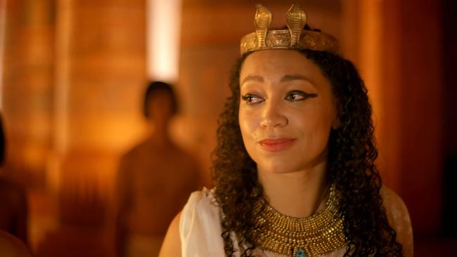 Pharaonin Teje mit Krone am Kopf blickt freundlich umher