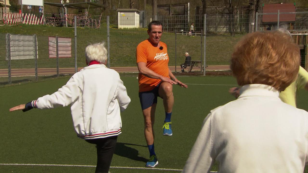 Philipp Jelinek trainiert mit Seniorinnen und Senioren auf einem Sportplatz