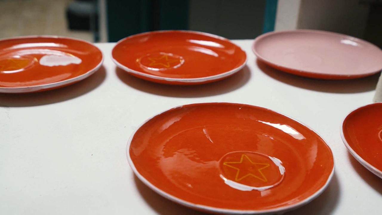 Fertige Keramiken, die in den Werkstätten auch in Serien produziert werden.(rote Untertassen mit gelbem Stern)