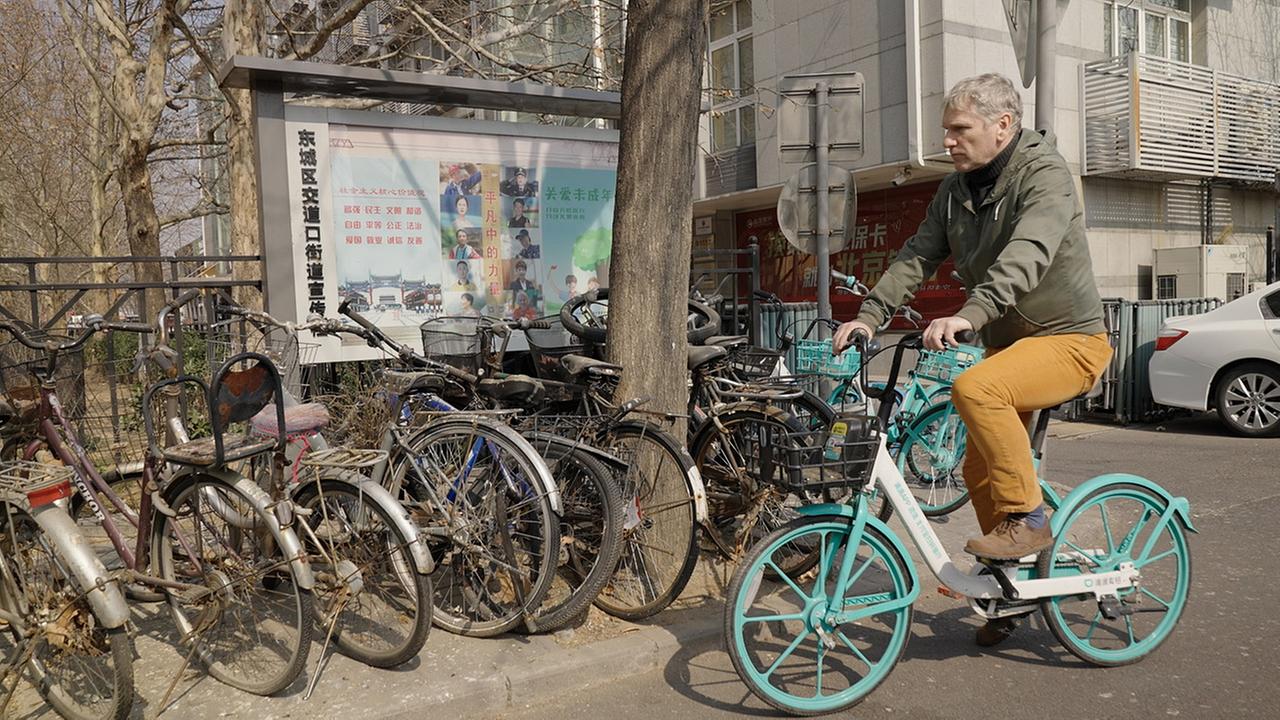 Korrespondent Josef Dollinger auf einem billigen Leihrad auf den Straßen Pekings.