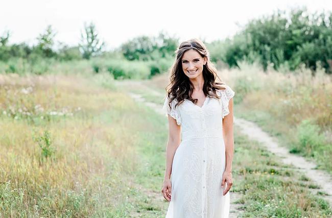 © Caterina Hoffmann Die Sängerin "Die Mayerin" steht in einem weißen Kleid auf einem frühlingshaften Feldweg