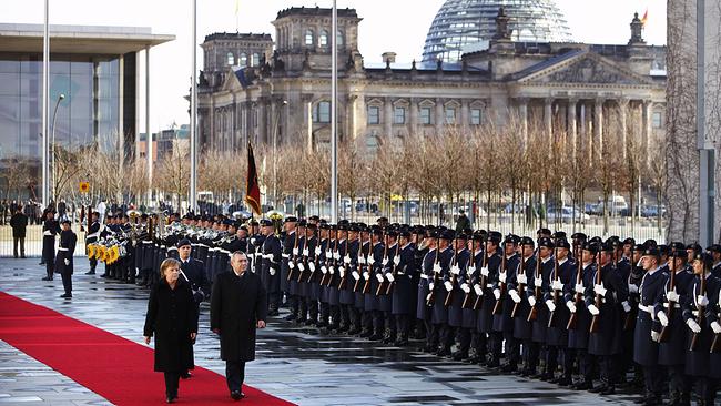 Angela Merkel schreitet bei militärischen Ehren eine Soldatenformation ab
