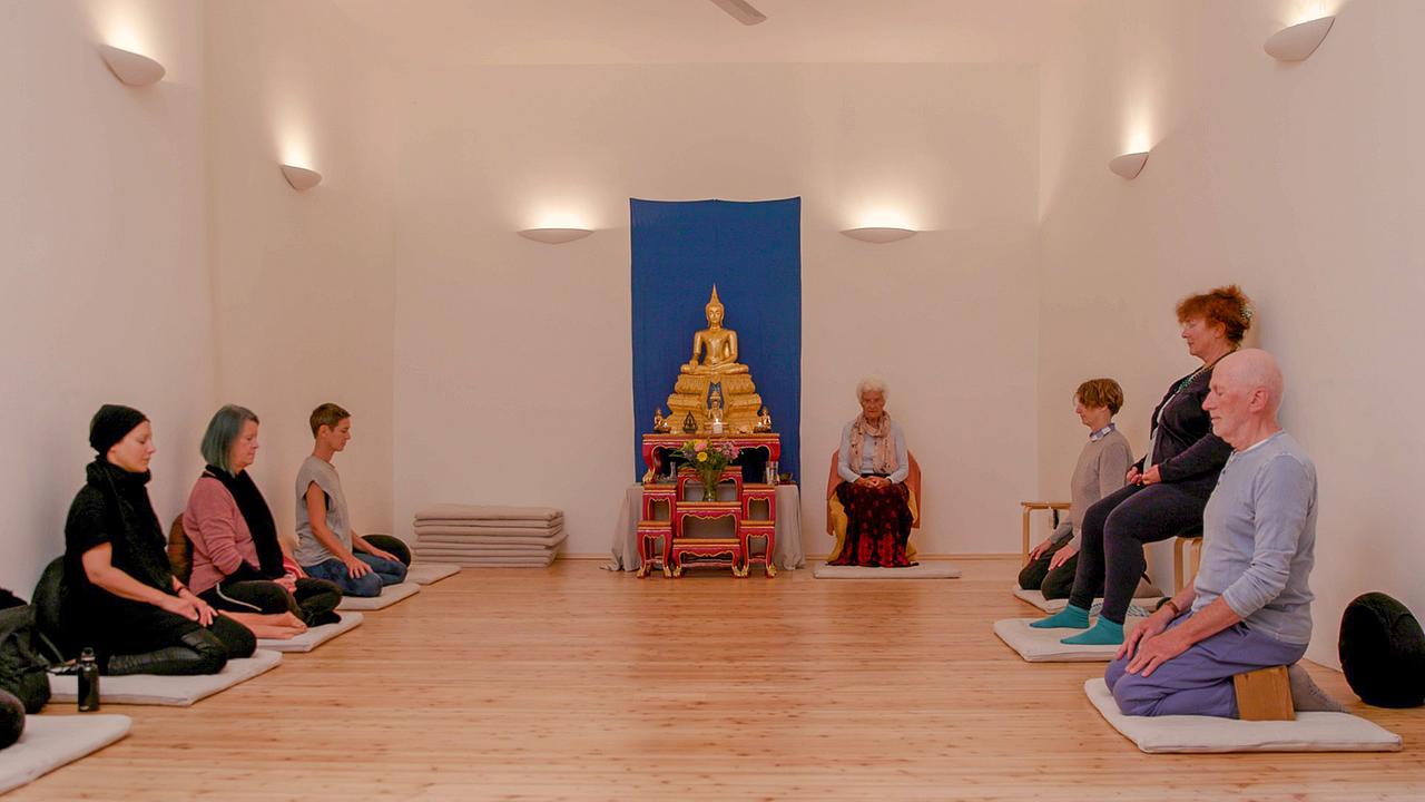 Die 93-jährige Ursula Lyon, von ihren Schülern die „Buddha-Oma“ genannt, hat das sogenannte Sampada-Yoga entwickelt. Sie kombiniert Körperübungen, Meditation und Atemübungen mit buddhistischer Weisheit. Im Zentrum ihrer Philosophie steht das Mitgefühl für sich selbst und andere.
