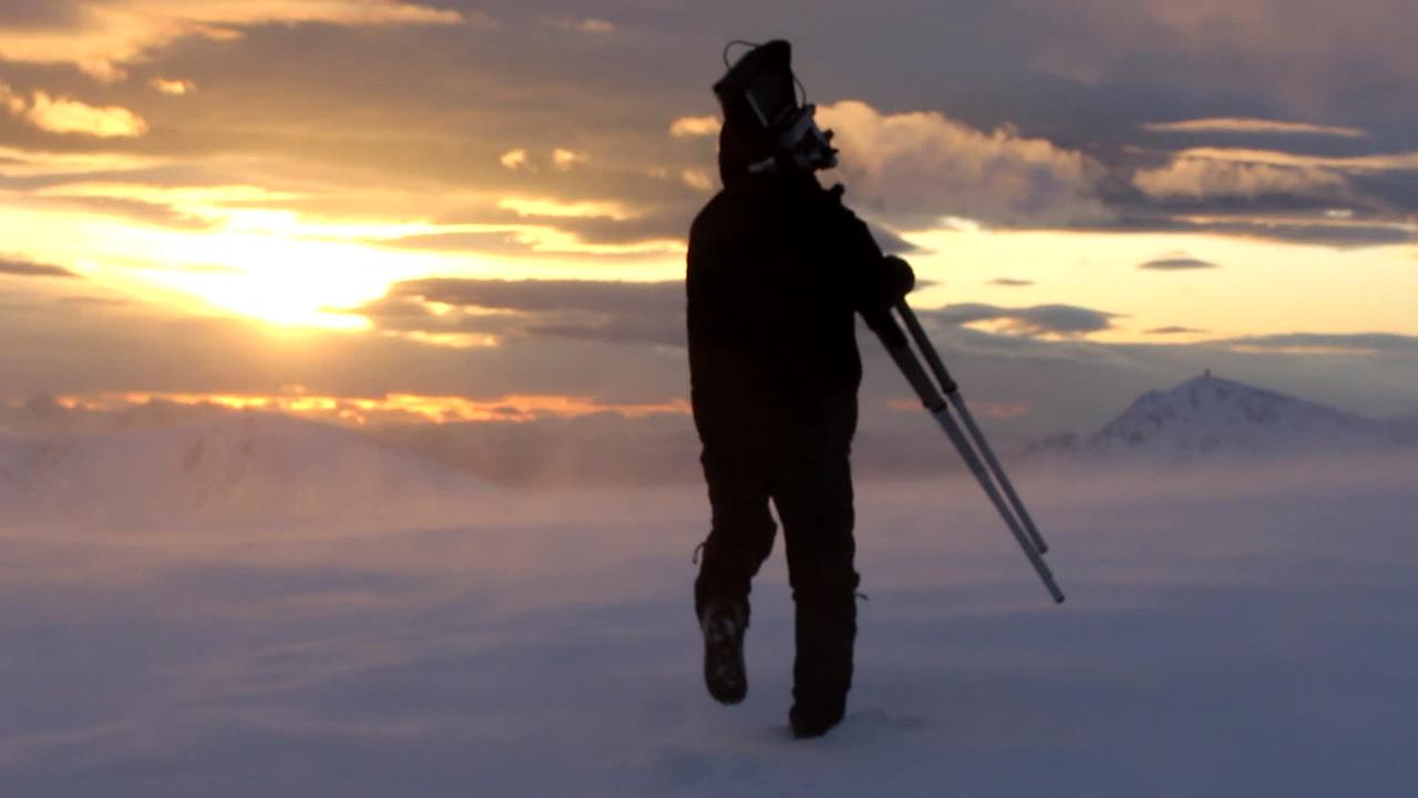 Gregor Sailer trägt Kamera im Schneefeld
