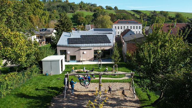 Kinderspielplatz mit Photovoltaikanlage auf Dach im Hintergrund