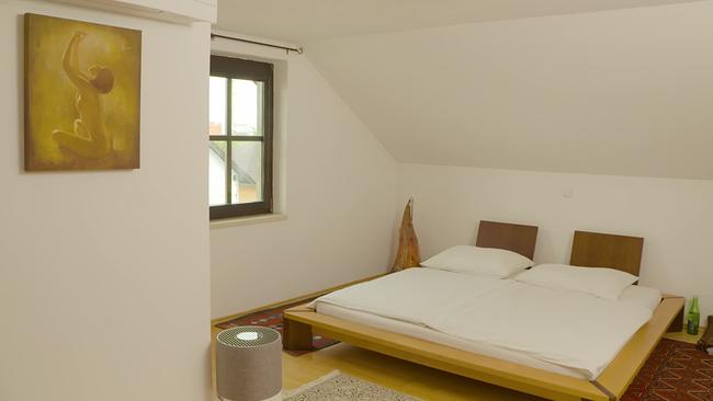 Ein Zimmer in dem ein hergerichtetes Doppelbett steht.