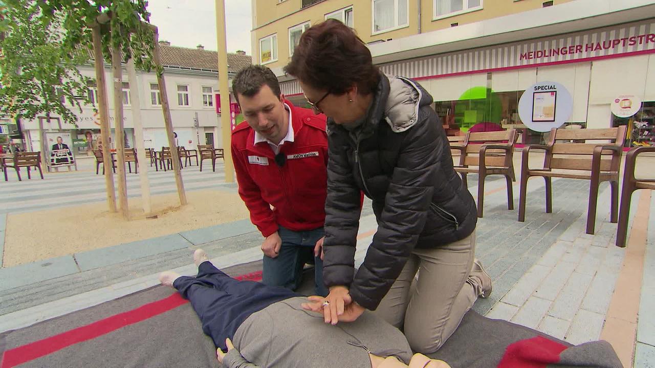 © ORF Sanitäter unterweist eine Frau wie Wiederbelebung funktioniert an einer Puppe.