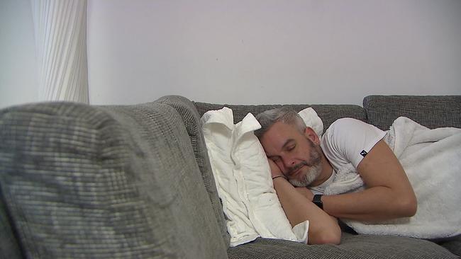 Mann liegt schlafend am Sofa