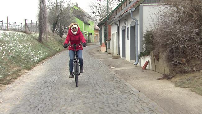 Frau fährt in Winterkleidung am Fahrrad durch ländlichen Ort