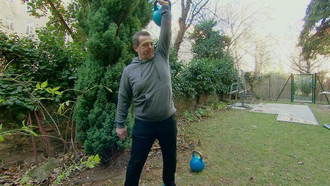 Mann trainiert mit Kettlebell im Garten