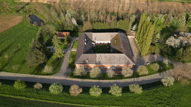 Vierkanter aus der Vogelperspektive in grüner Landschaft mit kleinem Teich daneben